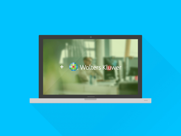 Laptop som visar Wolters Kluwers logotyp över en suddig kontorsbild