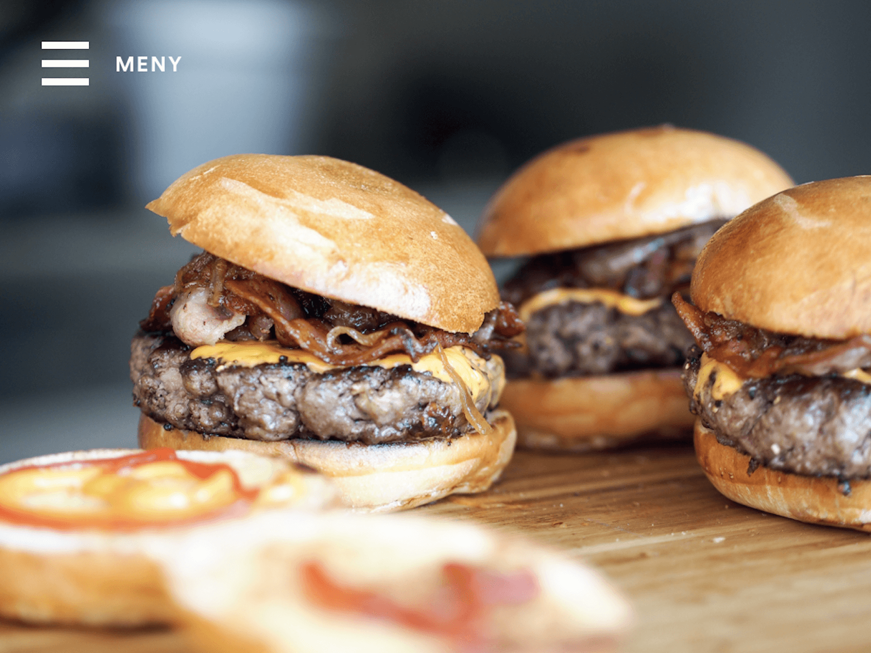 Hamburgare på en träbricka med en hamburgermeny-ikon och texten ”Meny” i hörnet