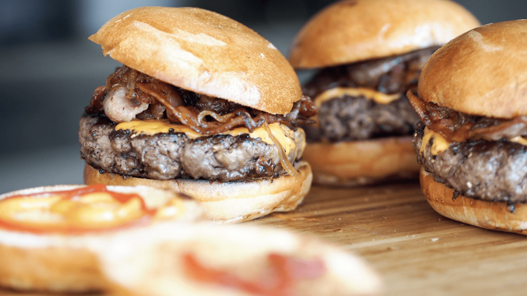 Hamburgare på en träbricka med en hamburgermeny-ikon och texten ”Meny” i hörnet