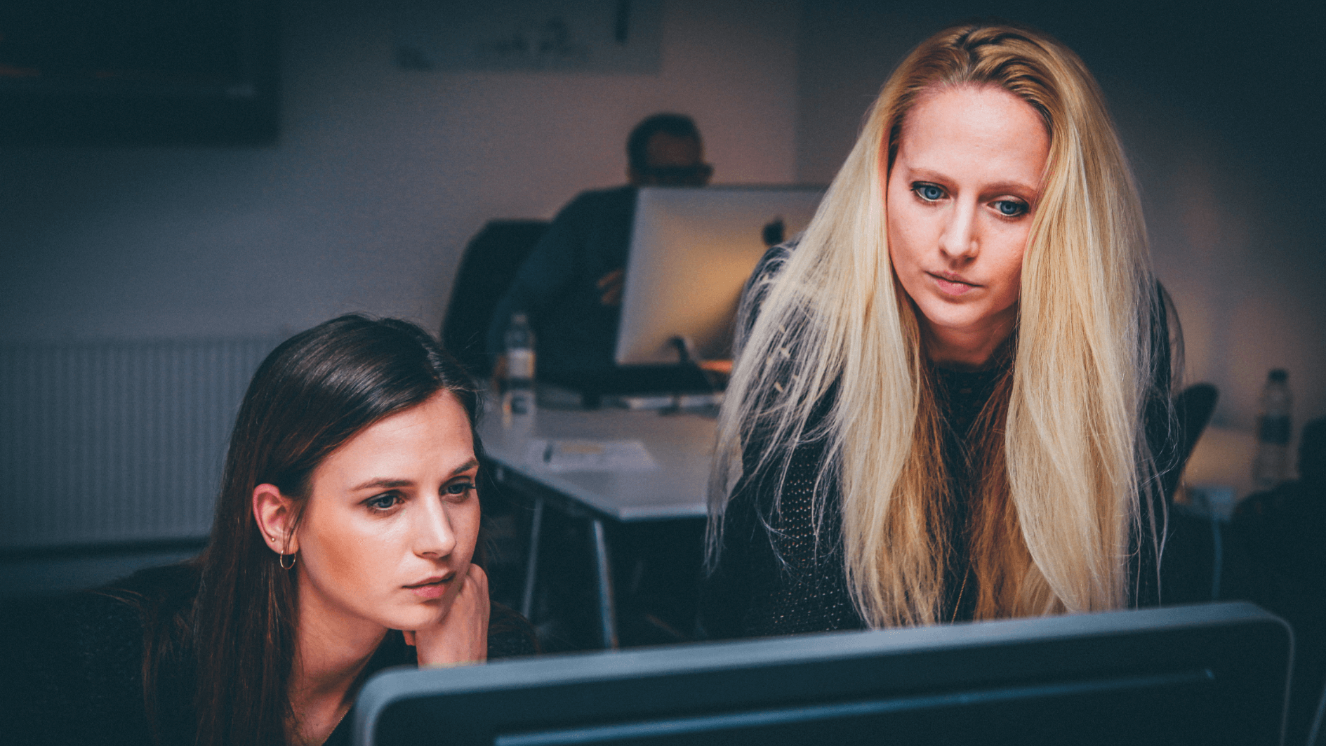Två kvinnor som tittar koncentrerat på en datorskärm på ett kontor