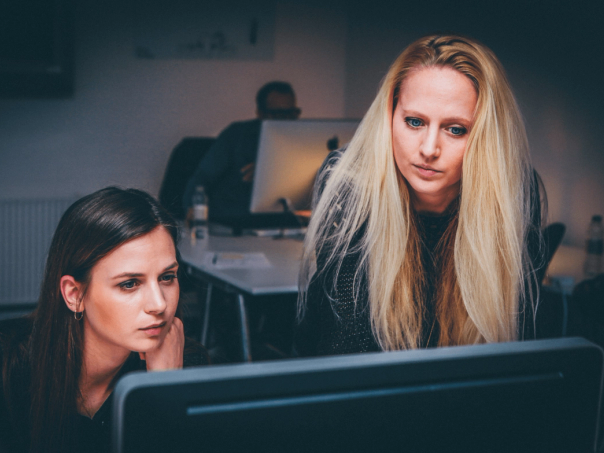Två kvinnor som tittar koncentrerat på en datorskärm på ett kontor