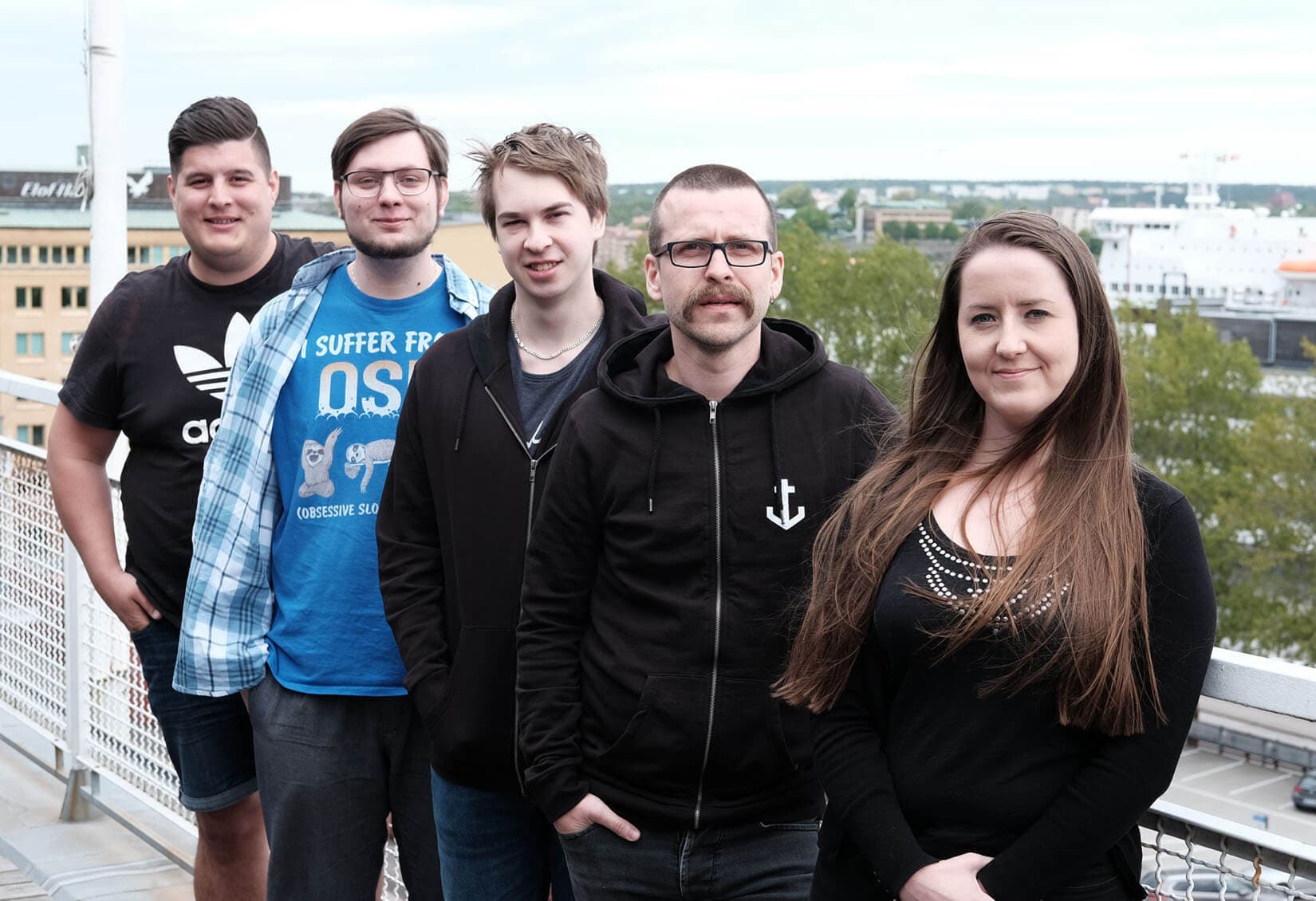 Foto på fem av Kodameras anställda, på kontorets balkong med Göteborgs skyline i bakgrunden