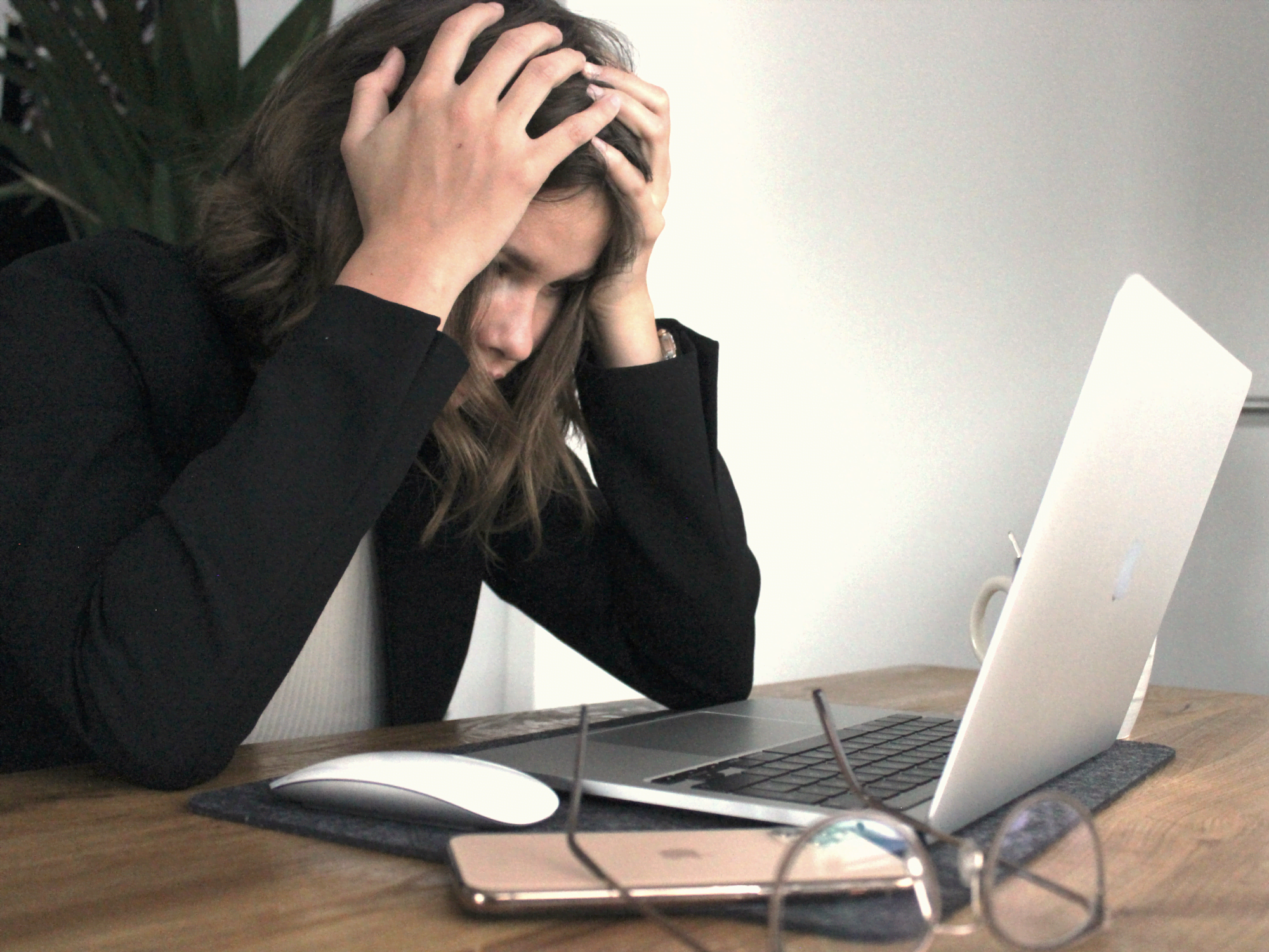 Bild på en person som sliter sitt hår framför en datorskärm