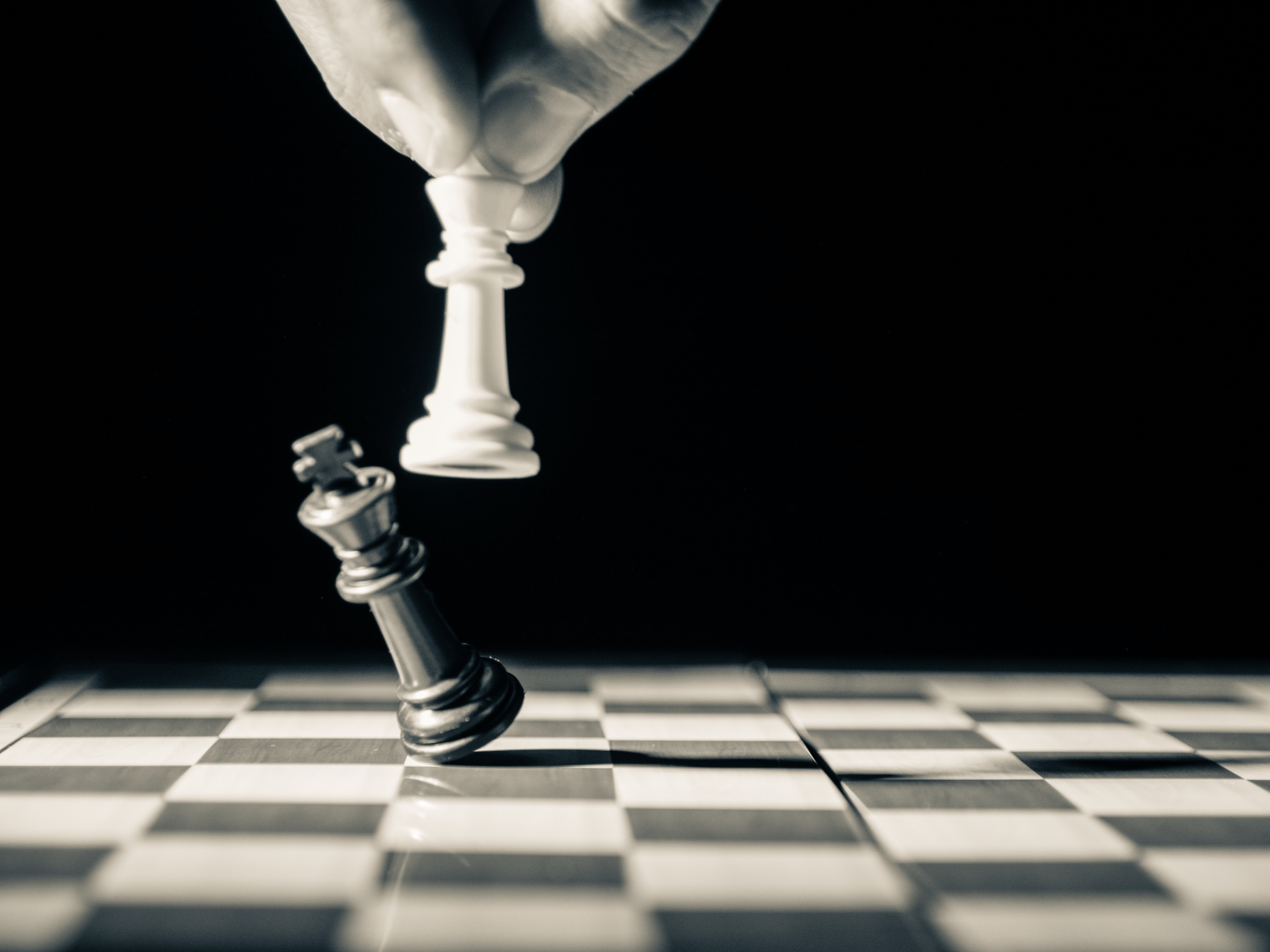 Svartvit bild med en schackpjäs som slår omkull kungen