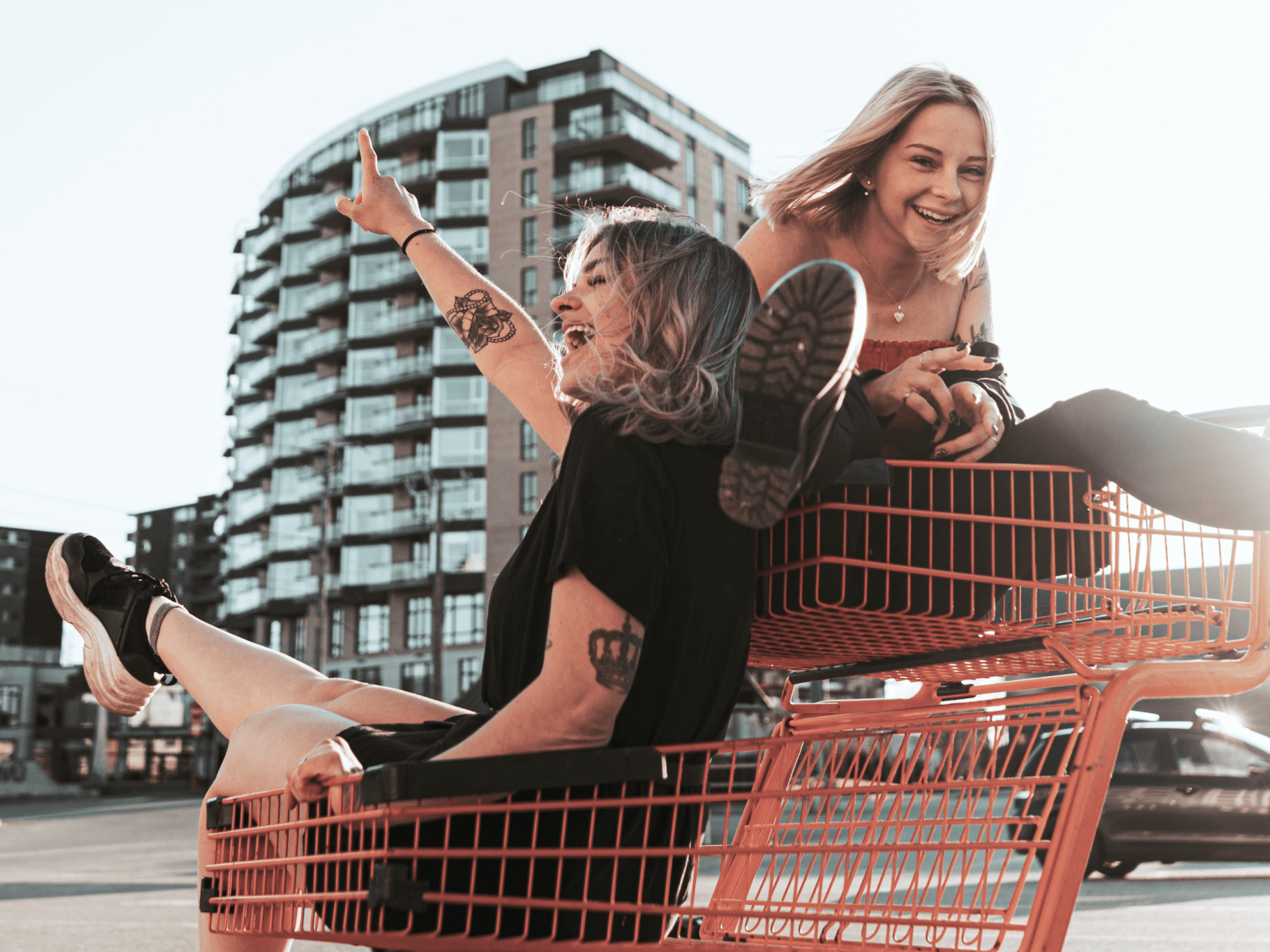 Två glada tjejer som sitter i en kundvagn