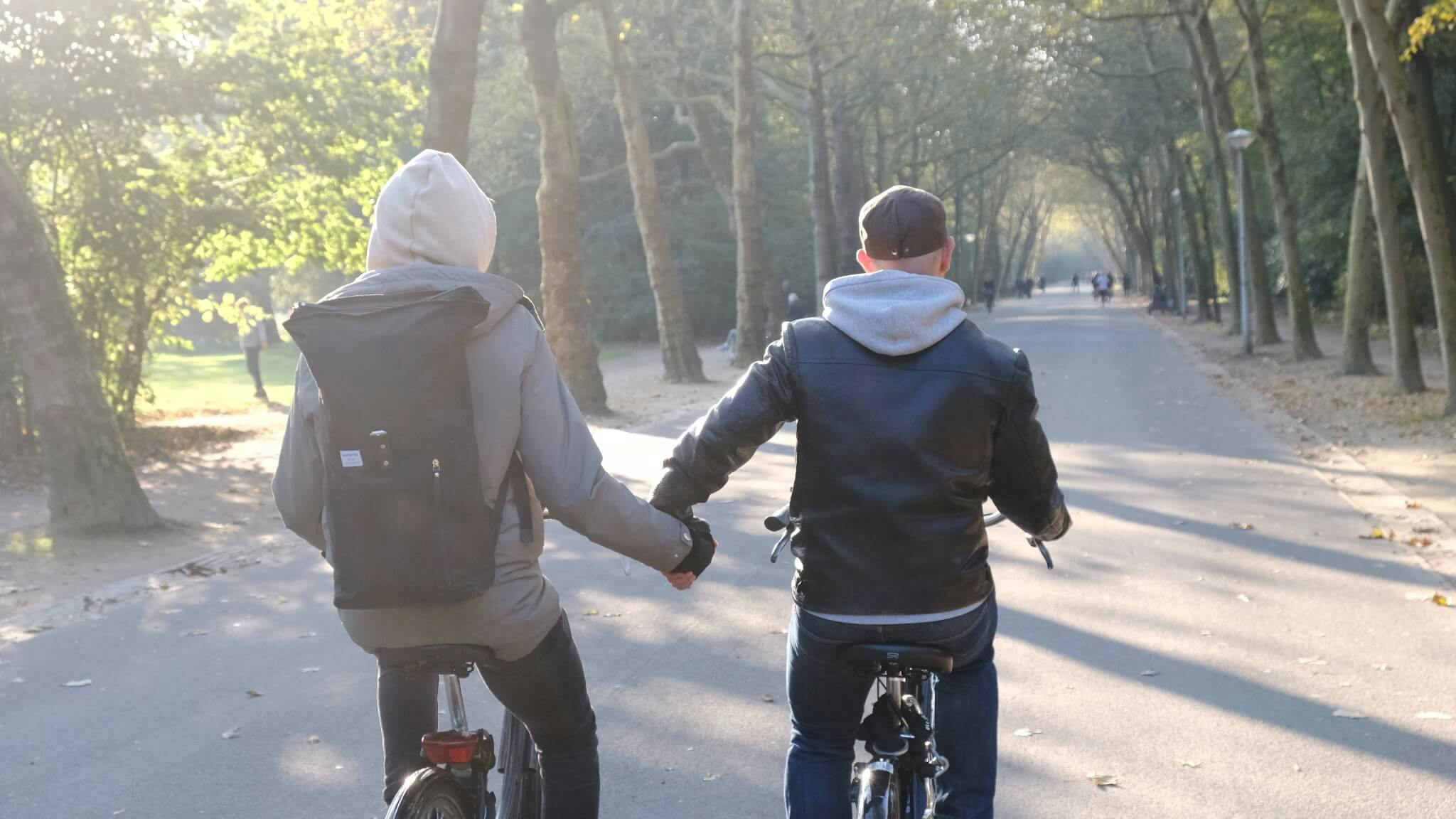 Två av våra kollegor på cykel, hållandes hand med varandra